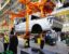 Workers at a Ford plant in Dearborn, Michigan, work beneath the body of a fully-electric Ford F-150 Lightning in 2022.