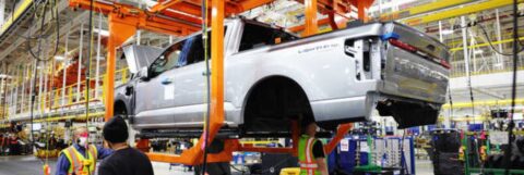 Workers at a Ford plant in Dearborn, Michigan, work beneath the body of a fully-electric Ford F-150 Lightning in 2022.