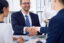 Business handshake at meeting or negotiation in the office, close-up. Partners are satisfied because signing contract or financial papers